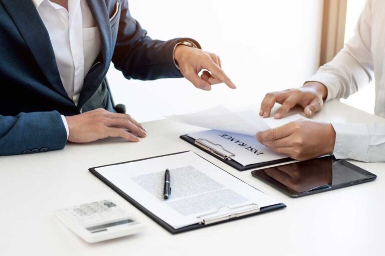 A person photographs a diamond ring beside its appraisal and home inventory records.
